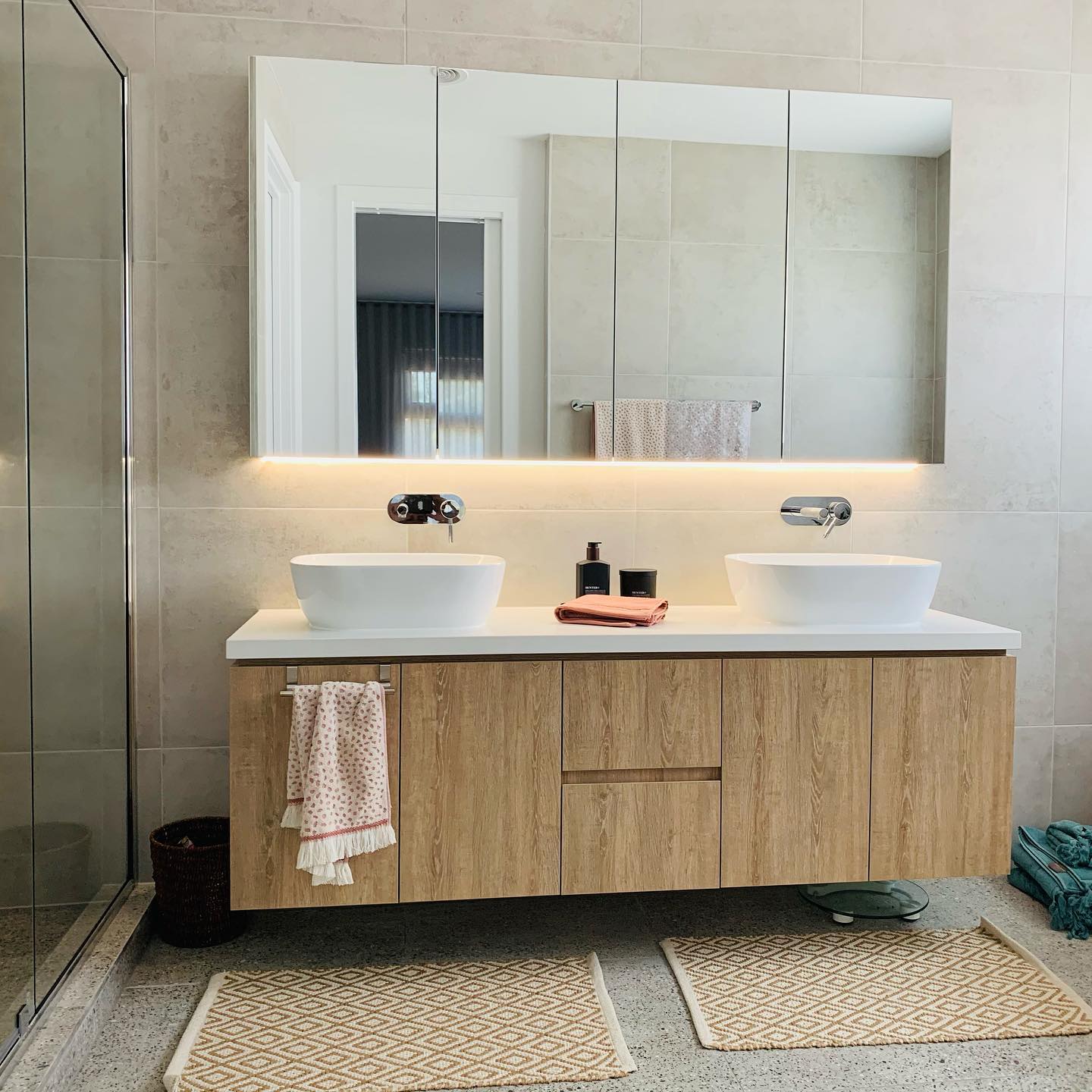 Double vanity with two vessel basins and a warm LED strip glowing under the mirrored cabinet