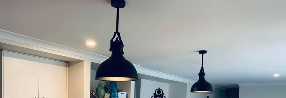 Two black dome pendant lights hanging over a kitchen and living area