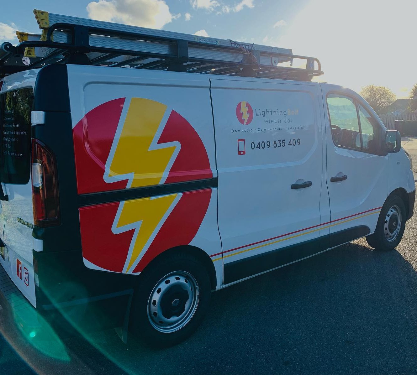 The white LightningBolt Electrical van with its red and yellow lightning bolt wrap and a ladder rack on the roof